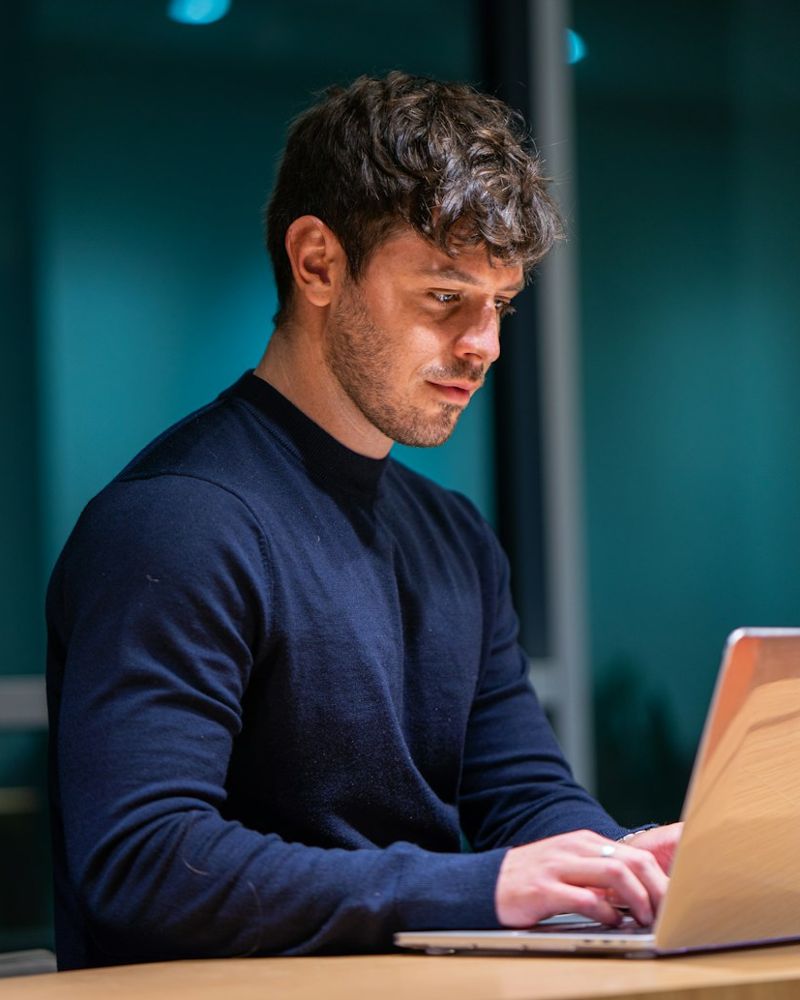 Homem trabalhando no laptop, em ambiente escuro
